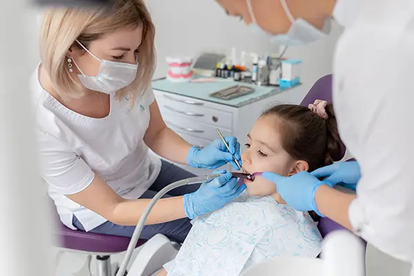 Dentist performing a root canal treatment on a young child in a dental clinic.